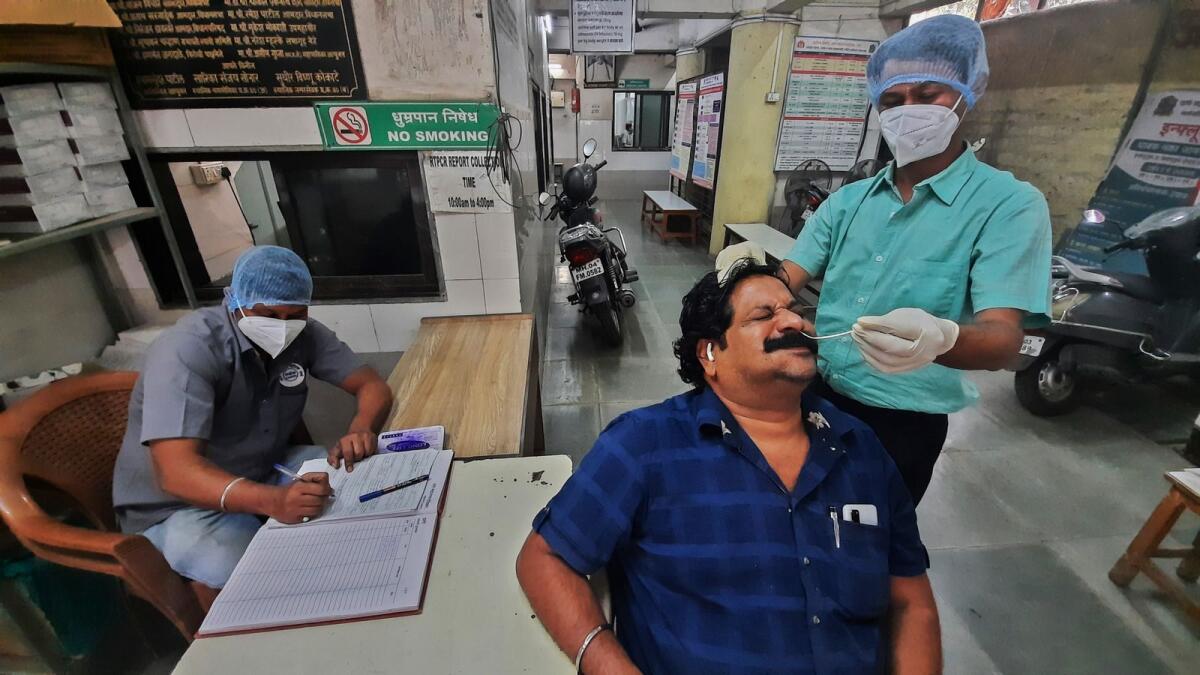 Health officials perform Covid-19 test on a man at the Municipal Corporation Hospital in Thane on Friday. Photo: PTI