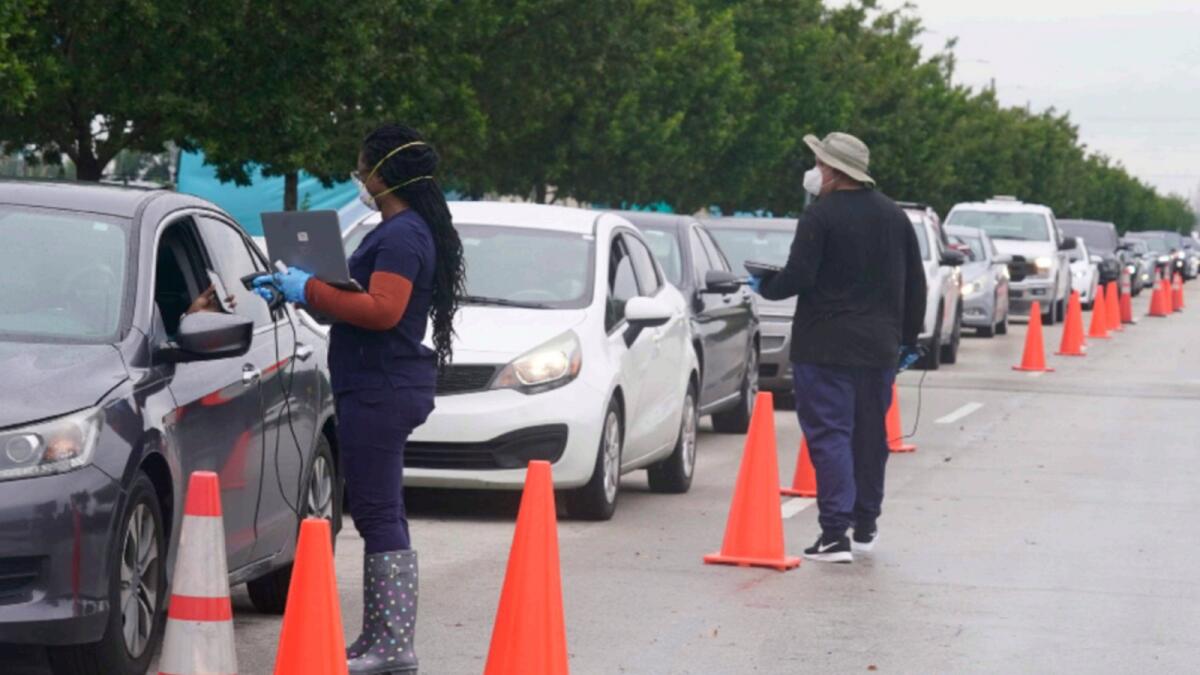 Employees of Nomi Health check in a long line of people for Covid-19 tests in North Miami. — AP