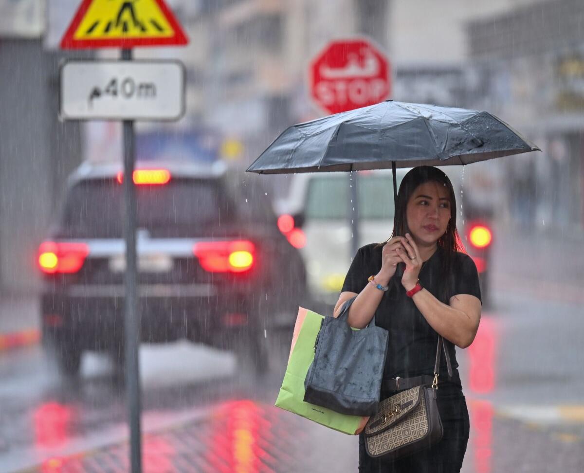 A resident uses umbrella to protect herself from rain on Monday morning. KT photo: Muhammad Sajjad