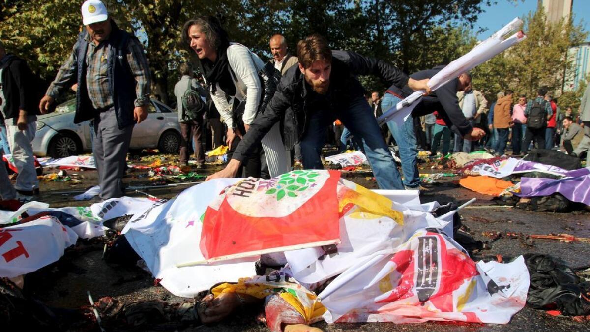People ask for help and cover the dead bodies with banners after an explosion during a peace march in Ankara, Turkey