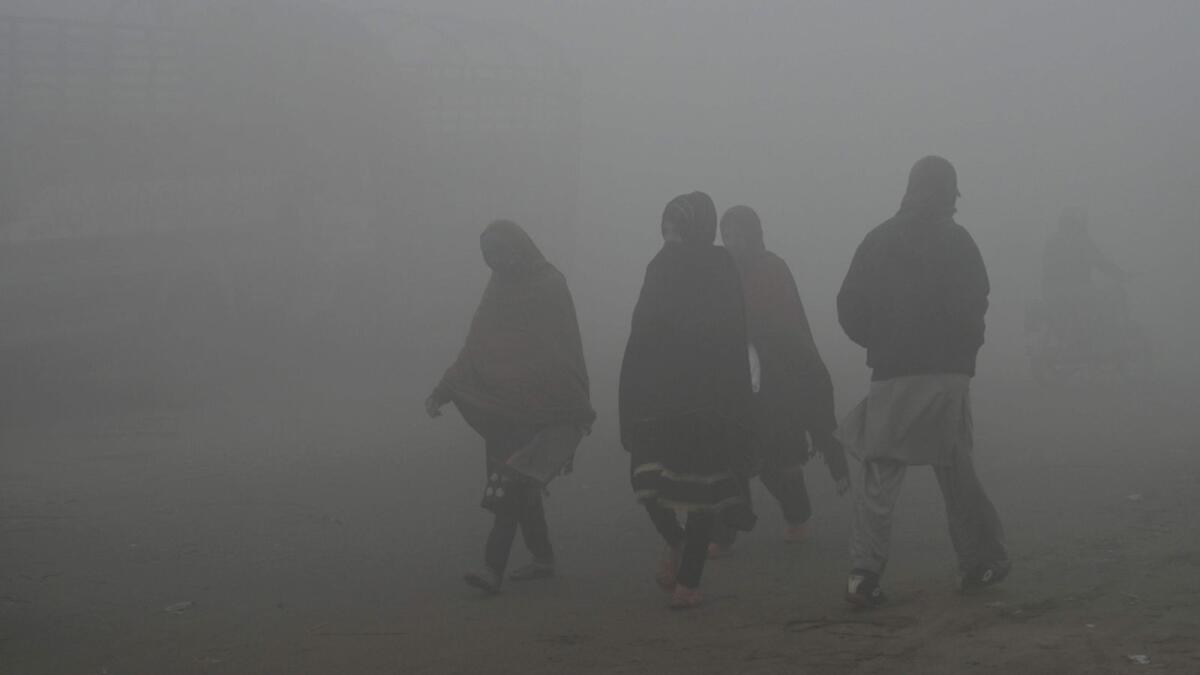 People walk through heavy smog on the outskirts of Lahore. Photo: AFP