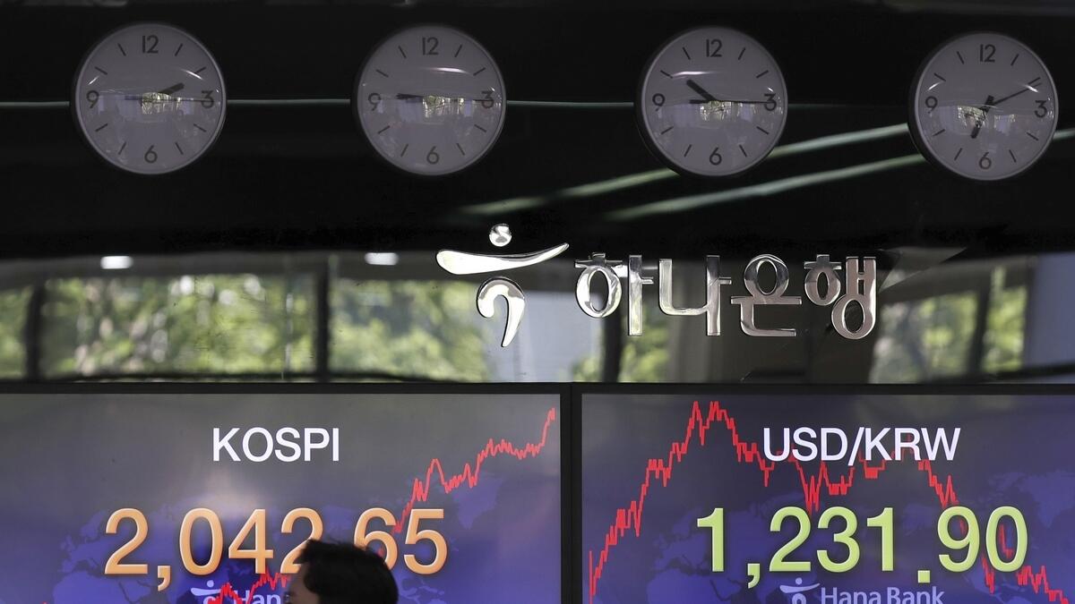A currency trader walks by the screens showing the Korea Composite Stock Price Index (KOSPI), left, and the foreign exchange rate between US dollar and South Korean won at the foreign exchange dealing room in Seoul, South Korea, onWednesday.-  AP