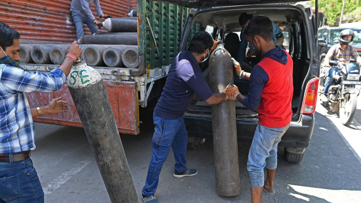 Workers of a wholesale supplier load medical oxygen cylinders in a car that are to be transported to hospitals. Photo: AFP