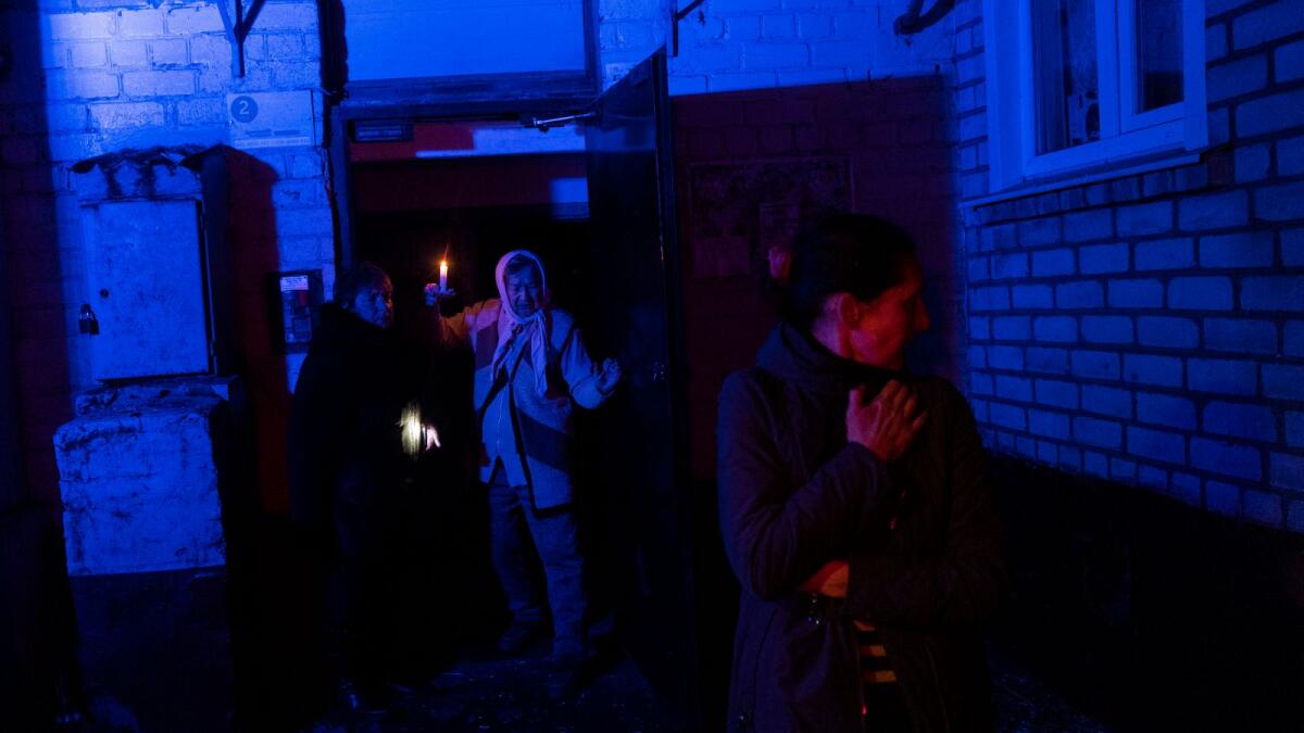 Residents stand outside a building that was shelled during a Russian attack in Kherson. — AP