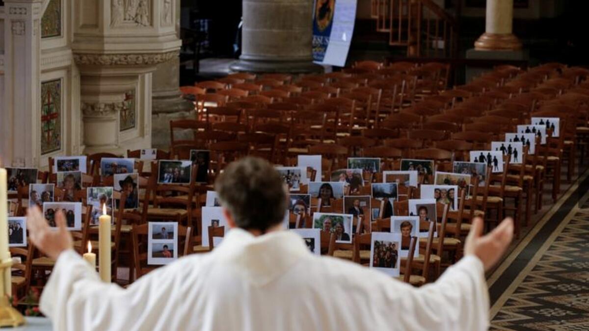 Priest Xavier Lemble holds the Easter mass with photos of believers who were asked to send in pictures after the service was closed in Bethune, France. Photo: Reuters