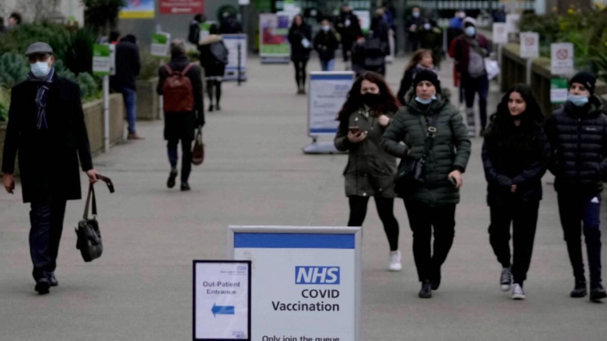 Pedestrians walk past a sign for St Thomas' Hospital Covid-19 vaccination centre in London. — AP