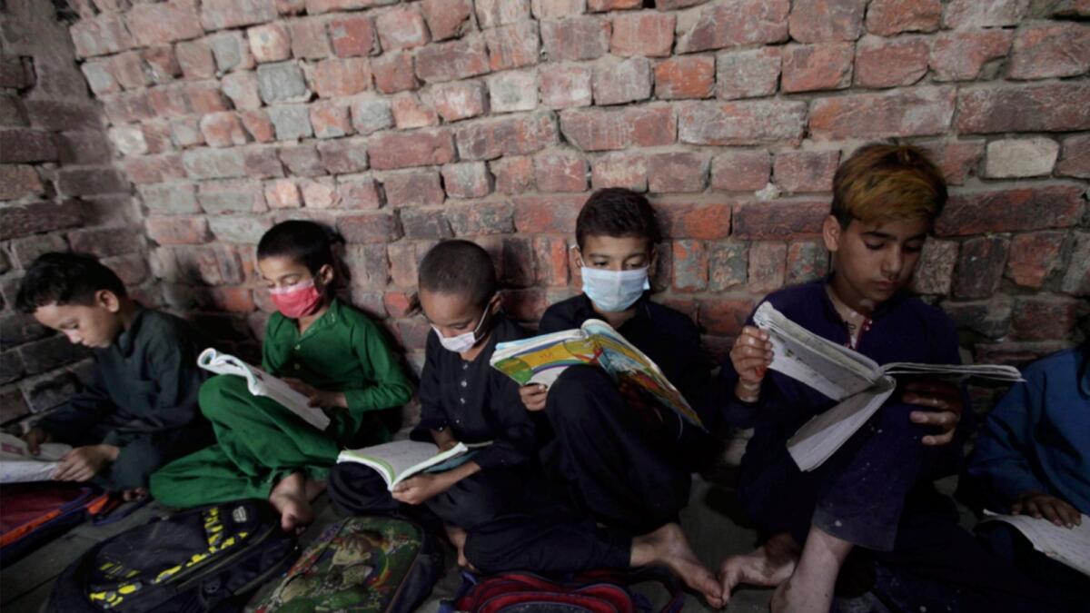 Afghan refugee children attend a tuition class administrated by a volunteer at a slum area on the outskirts of Lahore. — AP
