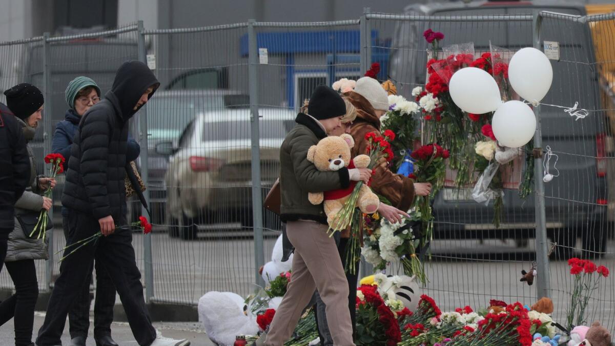 People place flowers and toys at the fence next to the Crocus City Hall, on the western edge of Moscow, following an attack on Friday. — AP