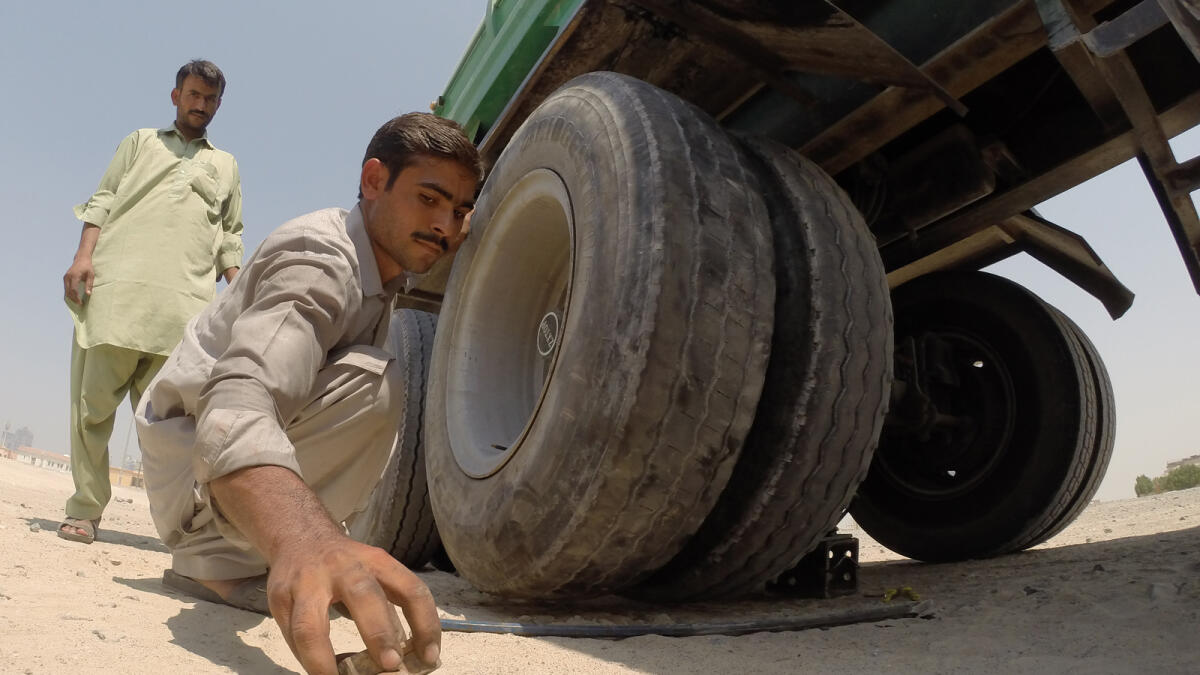 A truck driver is seen changing the tyre of his truck on a Dubai road.- Photo by Shihab/ Khaleej Times