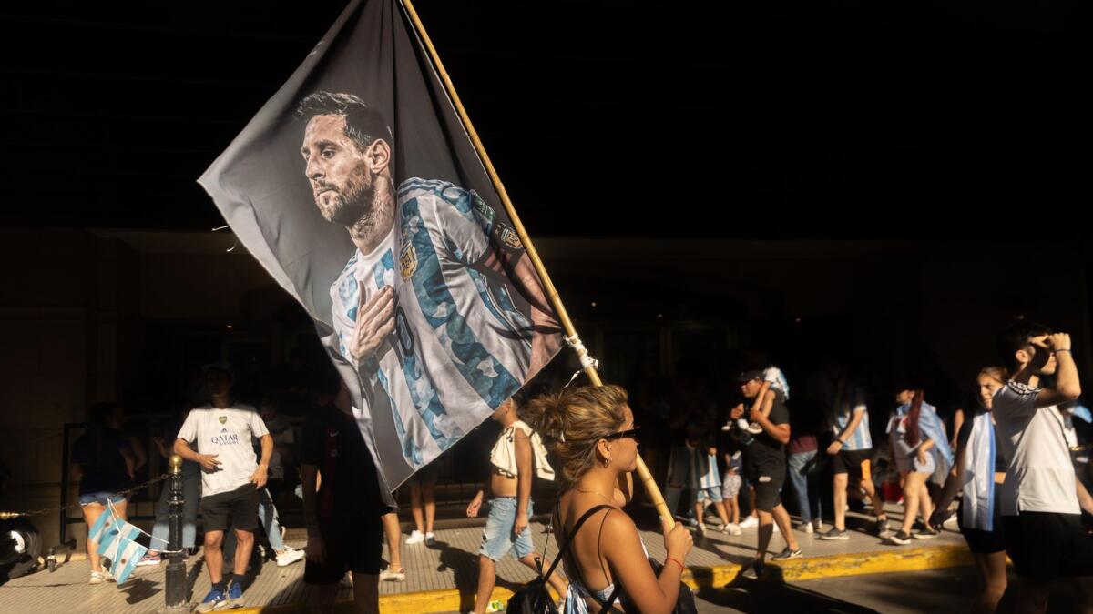 A fan of Argentina holds a flag with an image of Argentine forward Lionel Messi as she celebrates winning the Qatar 2022 World Cup against France at 9 de Julio avenue in Buenos Aires. (Photo by AFP)
