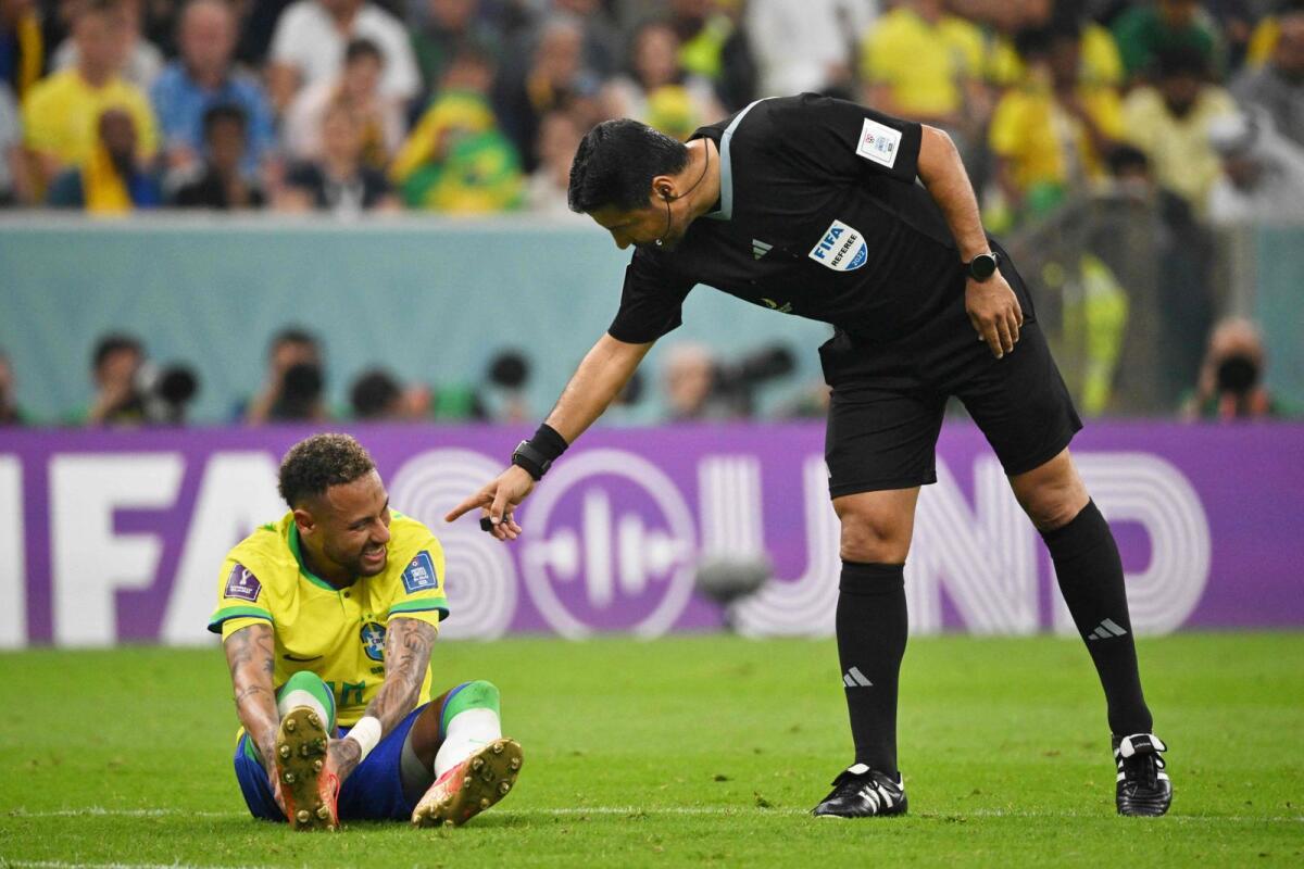 Iranian referee Alireza Faghani (right) gestures to Neymar after the Brazilian striker suffered an injury during the match against Serbia. (AFP)