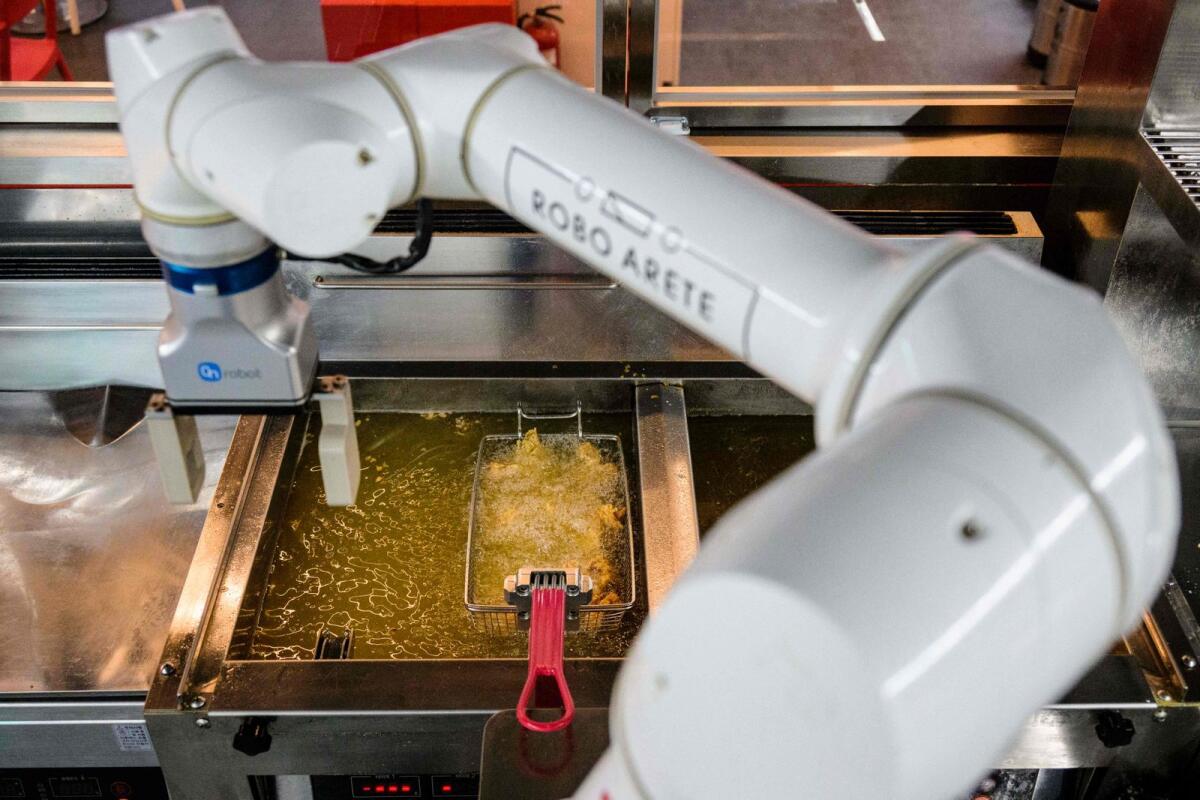In this photo taken on June 13, 2023, a robot is used to fry chicken at a Robert Chicken restaurant in Seoul.-- AFP