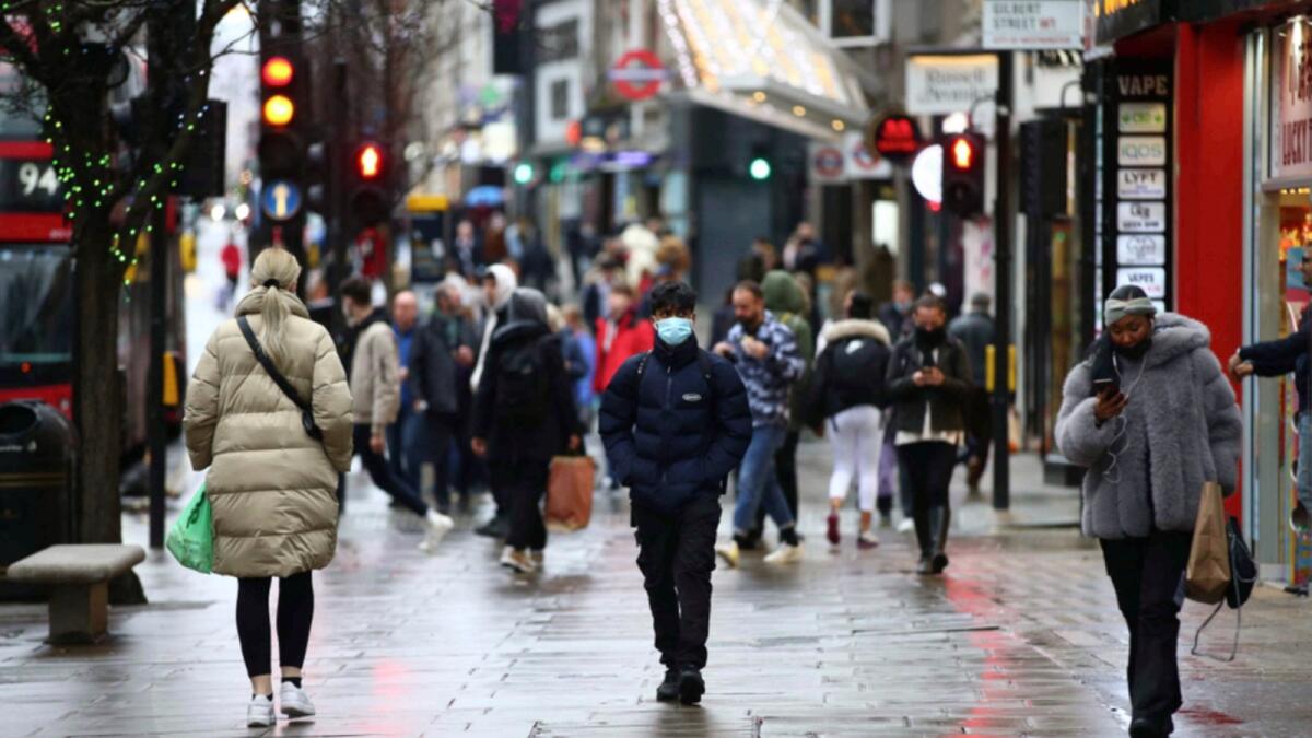 Shoppers, some wearing a facemask to combat the spread of Covid-19, walk along Oxford Street in London. — AFP