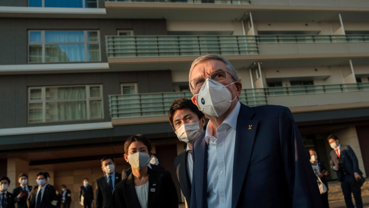 Thomas Bach (left) wearing a protective mask talks to journalists during a visit of Olympic and Paralympic village in Tokyo.— AP