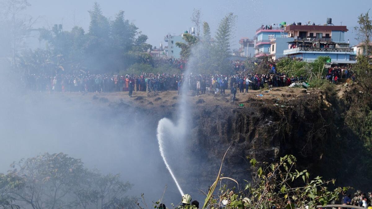 Fire brigade sprays water to douse a fire at the crash site.