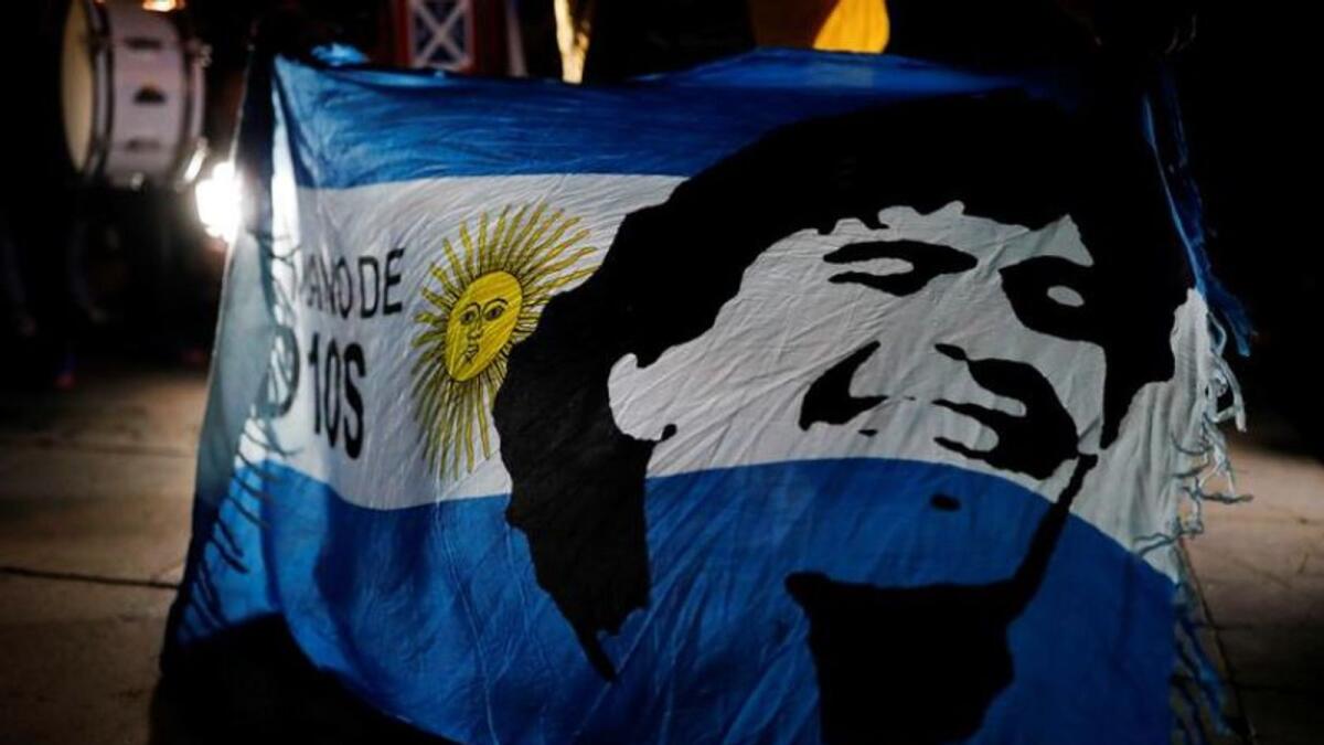 A fan holds an Argentine flag with the face of late Argentine soccer legend Diego Maradona painted on it during a tribute to him the day after his death in Barcelona, Spain, on Thursday. (Reuters)