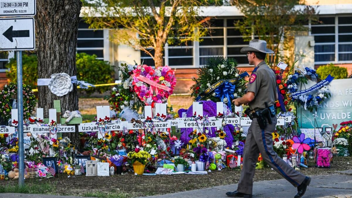 A police officer walks near the makeshift memorial for the shooting victims outside Robb Elementary School in Uvalde, Texas. AFP