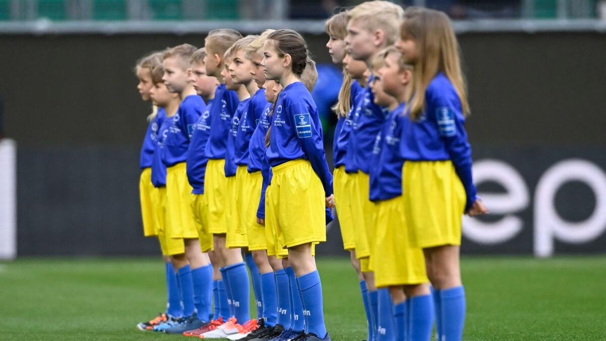 Children dressed in blue and yellow in support of Ukraine are pictured on the pitch before the match between Wolfsburg and Barcelona. (Reuters)