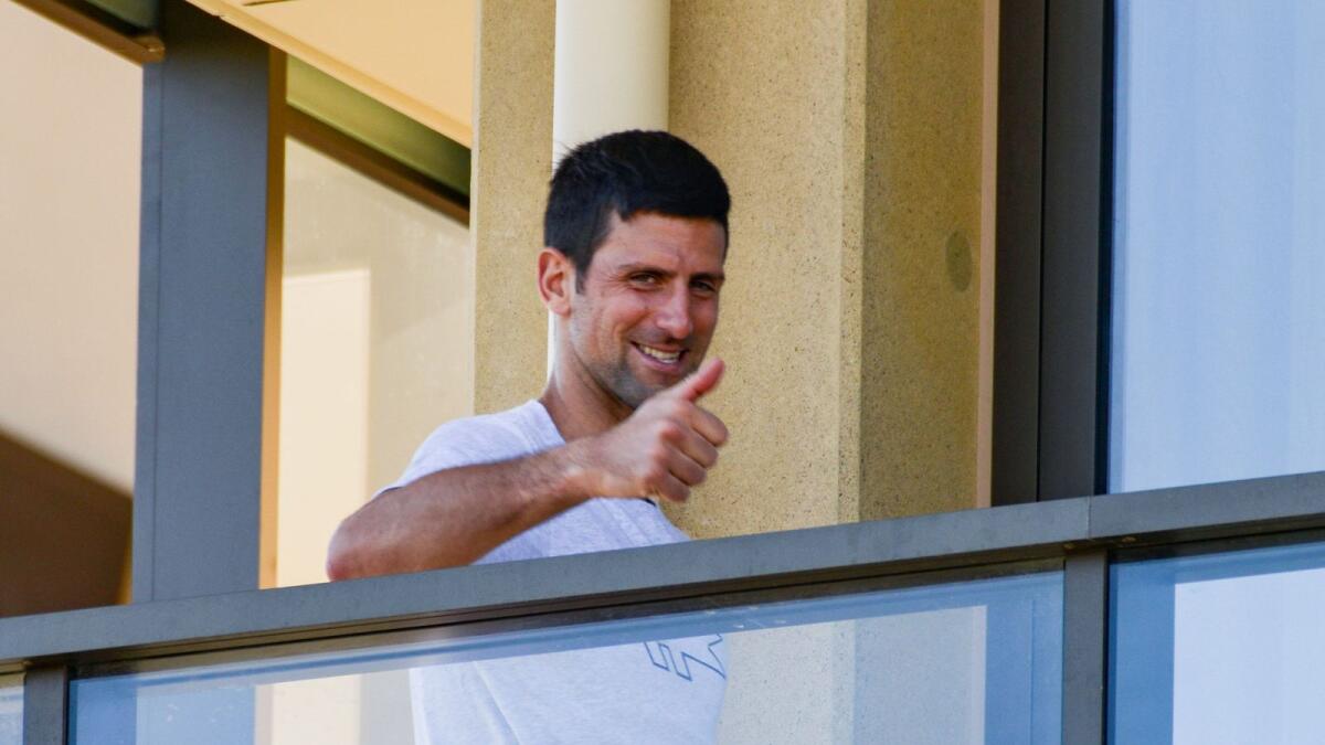 Novak Djokovic of Serbia gestures from his hotel balcony in Adelaide. — AFP