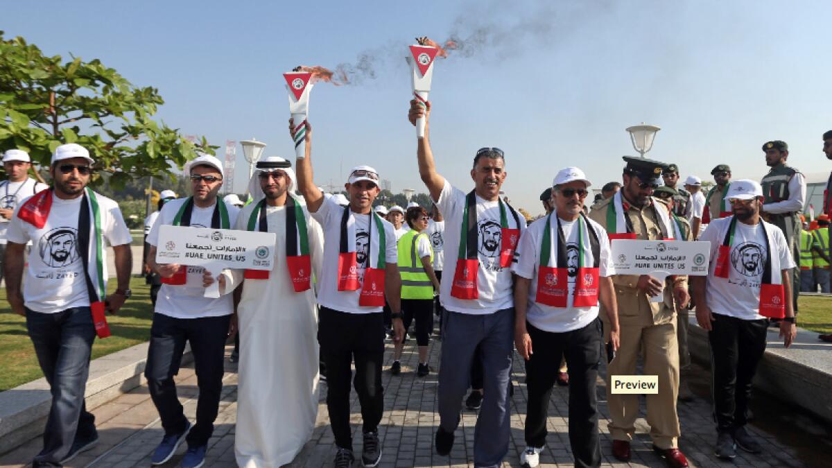 Dr Abdulla Al Karam, director General, KHDA, Ali Bujasim, Retired FIFA referee and Saeed Hareb, Secretary General of Dubai Sports Council leads the lighting of torch during the Zayed Torch Relay in honor of Sheikh Zayed bin Sultan Al Nahyan at the Etihad Museum in Dubai