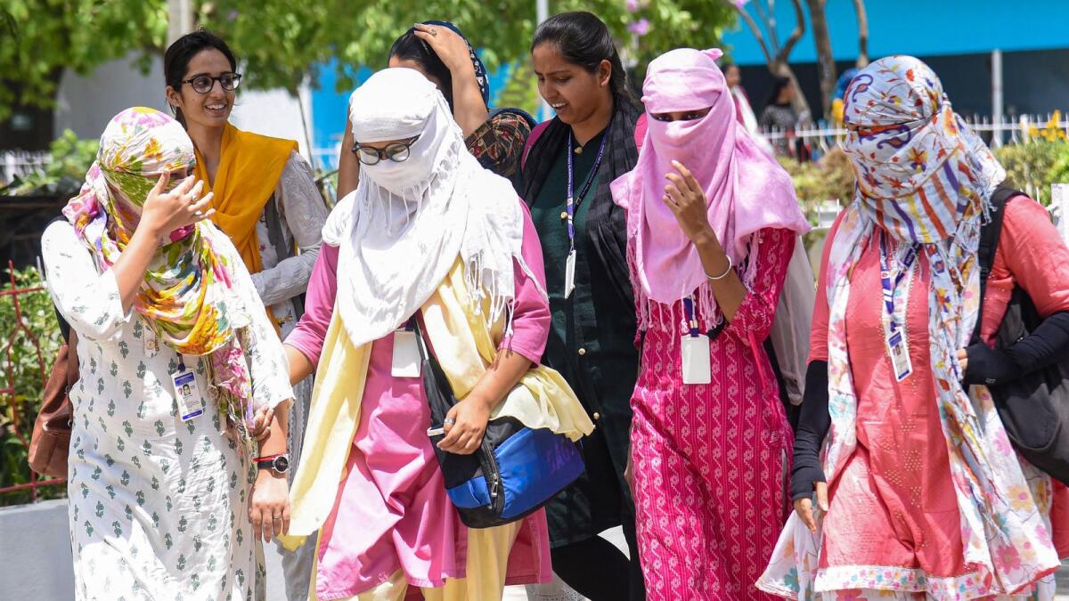 Young women use scarves to shield themselves from the hot summer sun in Patna on Thursday. — PTI