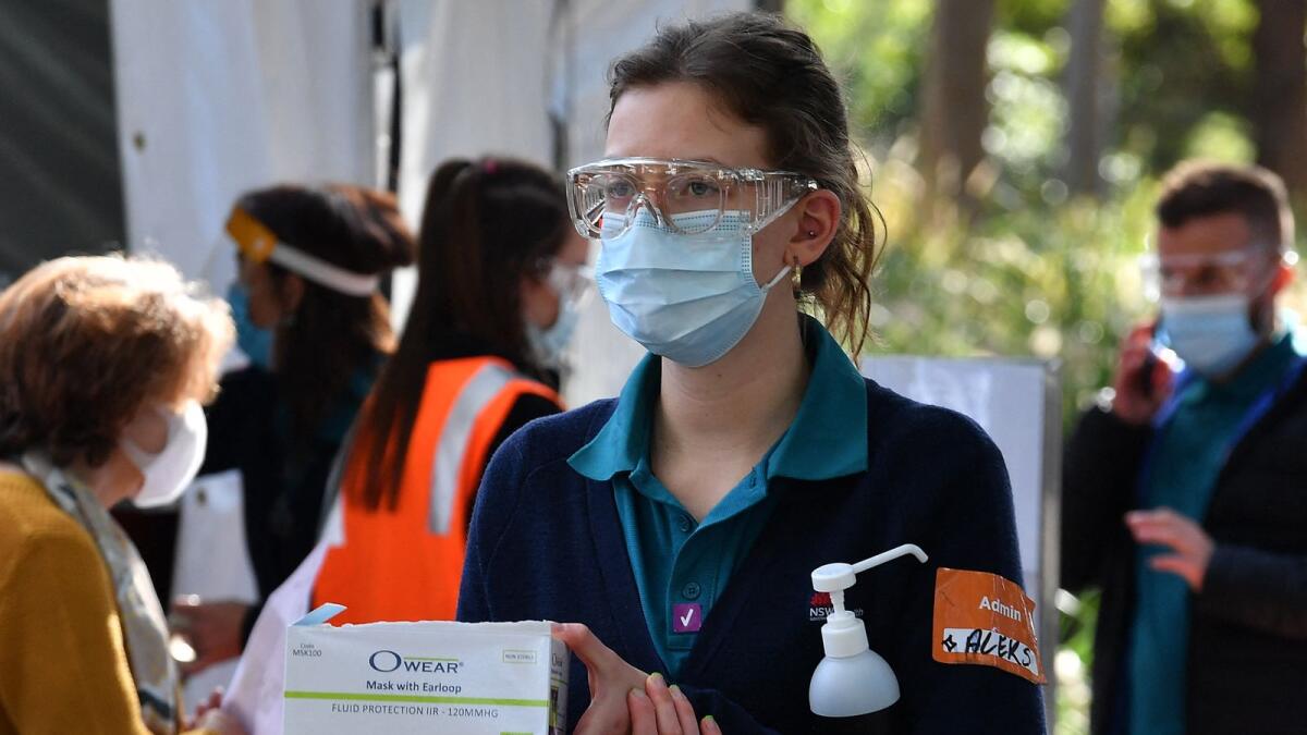 A health worker holds a box of face masks and hand sanitiser outside a Covid-19 vaccination centre in Sydney. Photo: AFP