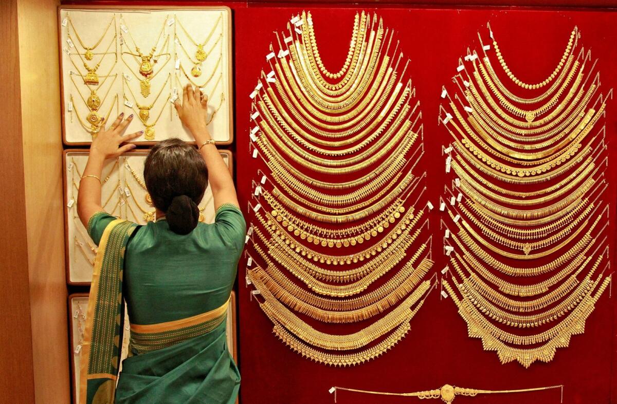 A saleswoman arranges a gold necklace inside a jewellery showroom. Photo: Reuters