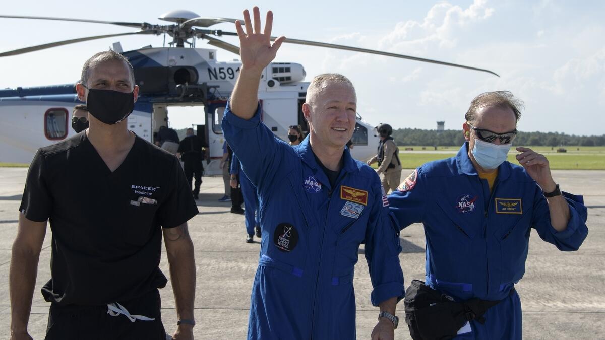 This handout photo released courtesy of NASA shows NASA astronaut waving to onlookers as he boards a plane at Naval Air Station Pensacola to return him and Behnken home to Houston.