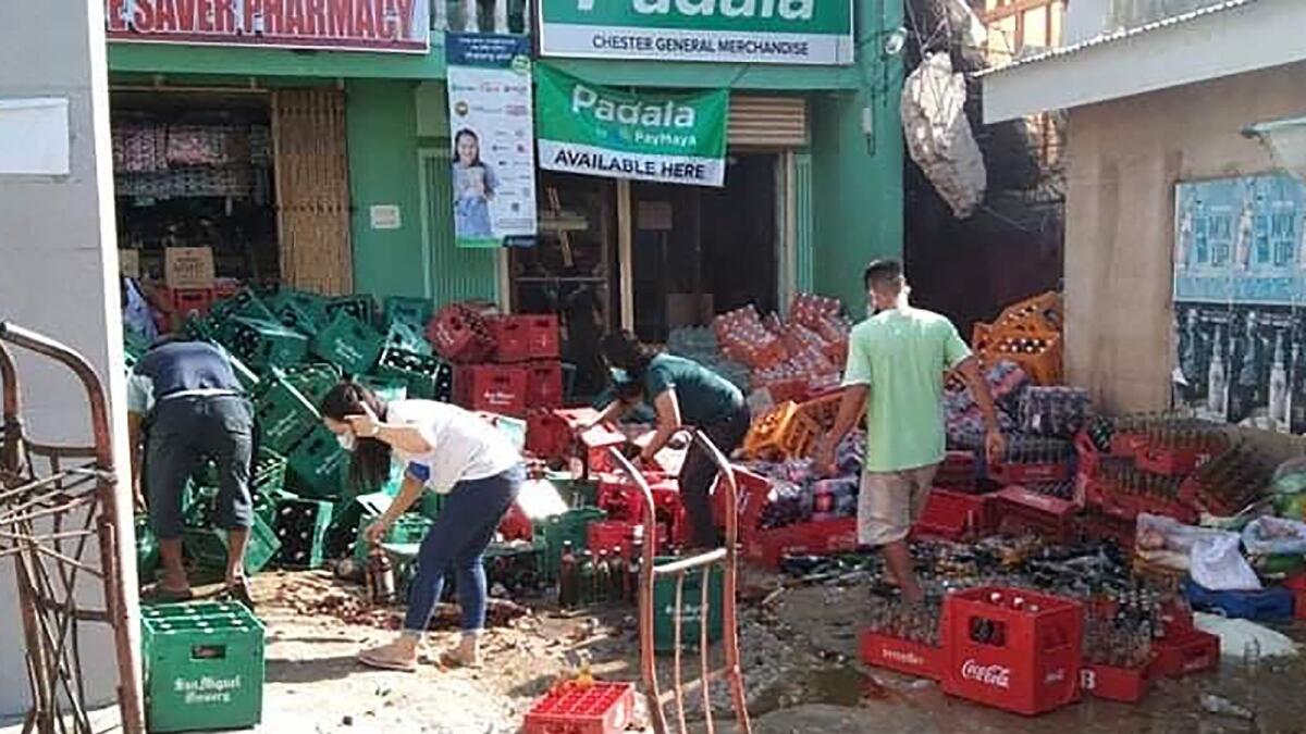 Shop workers clean up crates of fallen bottles after a 6.7-magnitude earthquake hit near the town of Cataingan in the central Philippine province of Masbate on August 18, 2020. - The strong earthquake shook the central Philippines on August 18, sending residents fleeing their homes and damaging buildings and roads, with at least one person reported killed. (Photo by Christopher Decamon / AFP)
