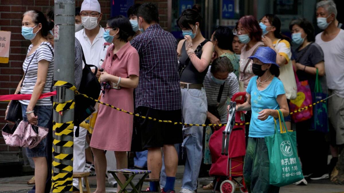 People wearing face masks line up outside a bakery shop to buy cookies in Shanghai. — AP