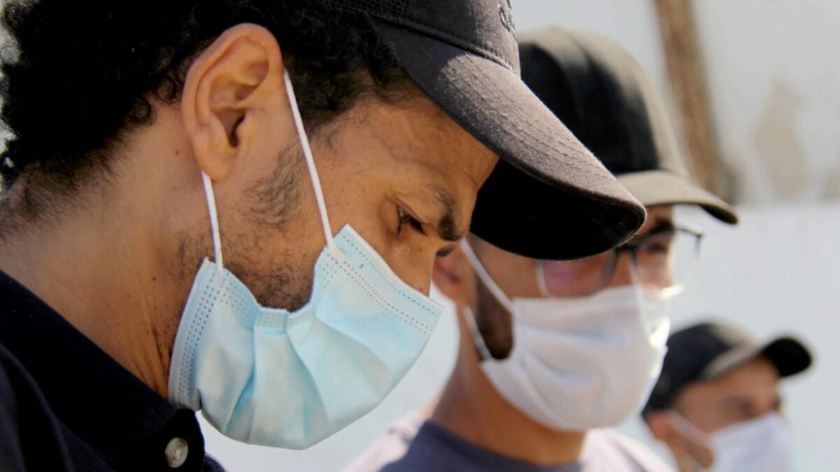 People wearing face masks to protect from Covid-19 stand outside a hospital in Tunis. — AP file