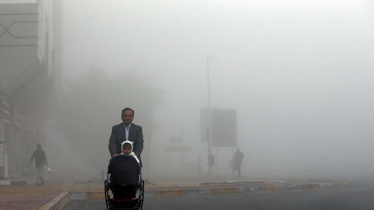 A father takes his child out through fog in Abu Dhabi on Monday. The weather will continue to be foggy till Friday. — Photo by Ryan Lim