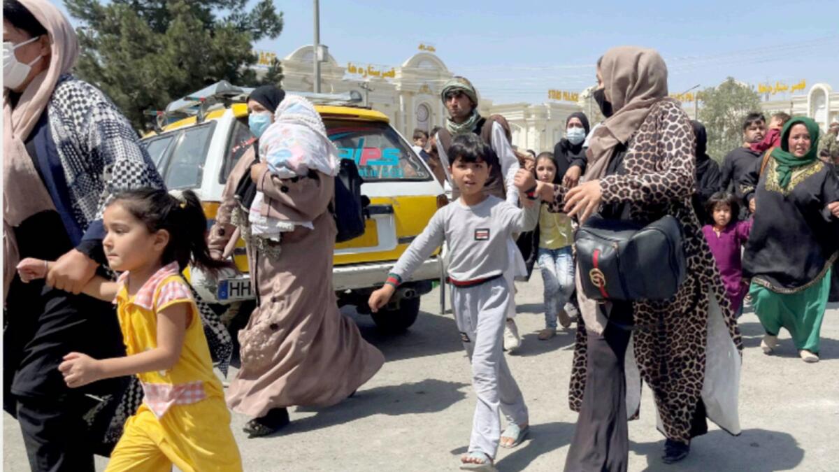 Women with their children try to get inside Hamid Karzai International Airport in Kabul. — Reuters