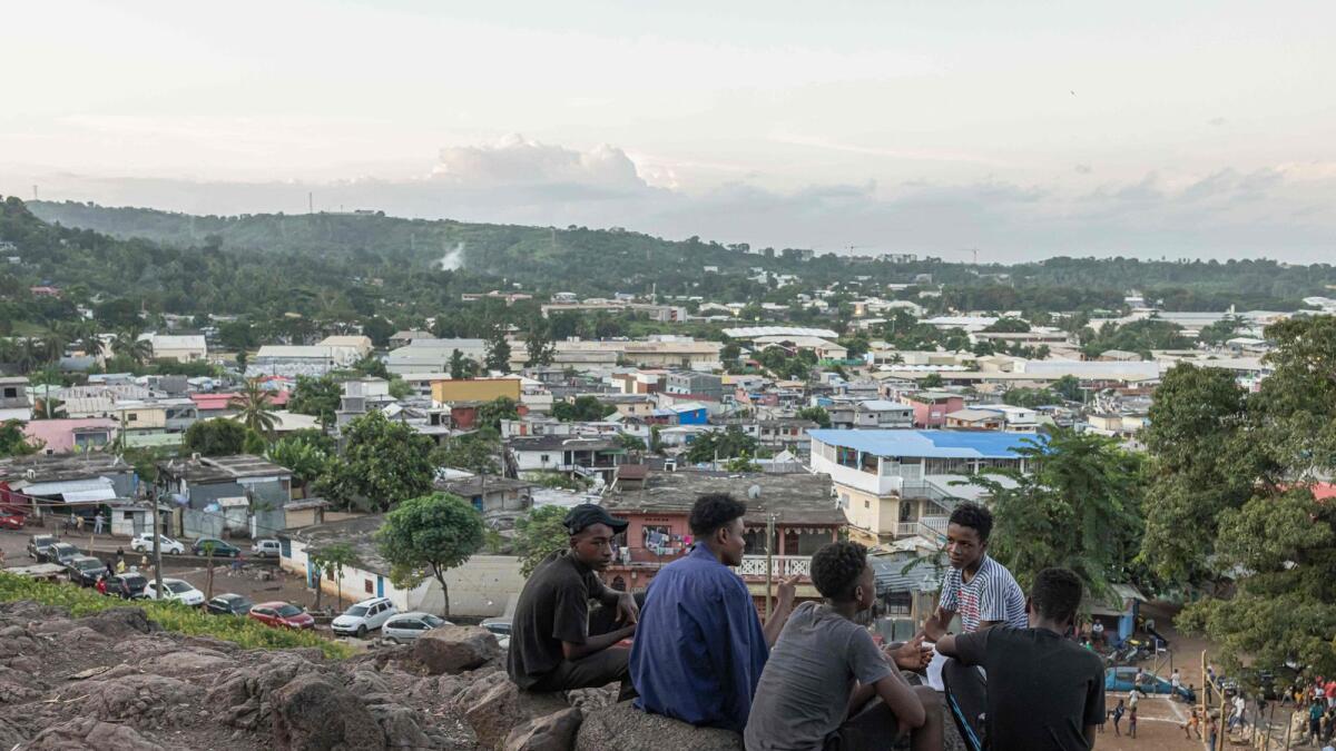 Boys speak as they sit on a hill overlook the village of Kaweni, near Mamoudzou, on the island of Mayotte on April 26, 2023. — AFP