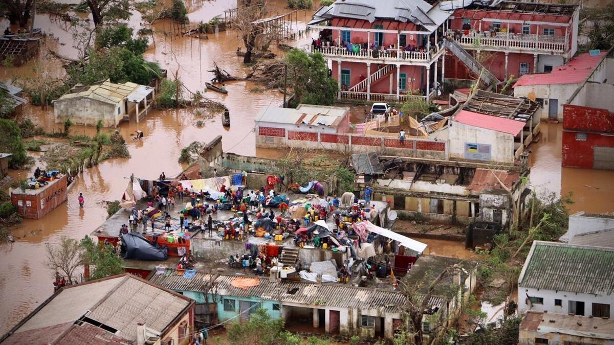 People gather on the roof of a house submerged by floods in Buzi.-AFP