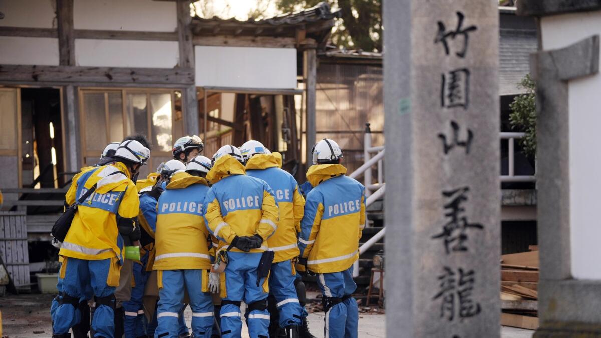Police officers huddle up before getting into a building at the premises of a temple to search for victims in Wajima in the Noto peninsula. — AP