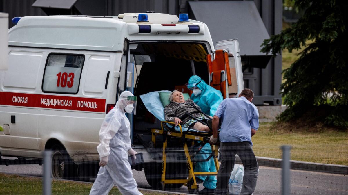 Medics escort a woman into a hospital where Covid patients are being treated near Moscow. photo: AFP