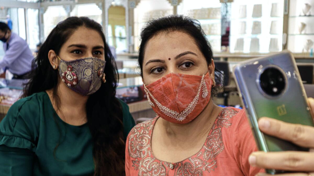 Customers wearing handmade facemasks studded with diamonds take selfie pictures at D Khushalbhai Jewellers showroom in Surat, some 270 km from Ahmadabad.  Photo: AFP