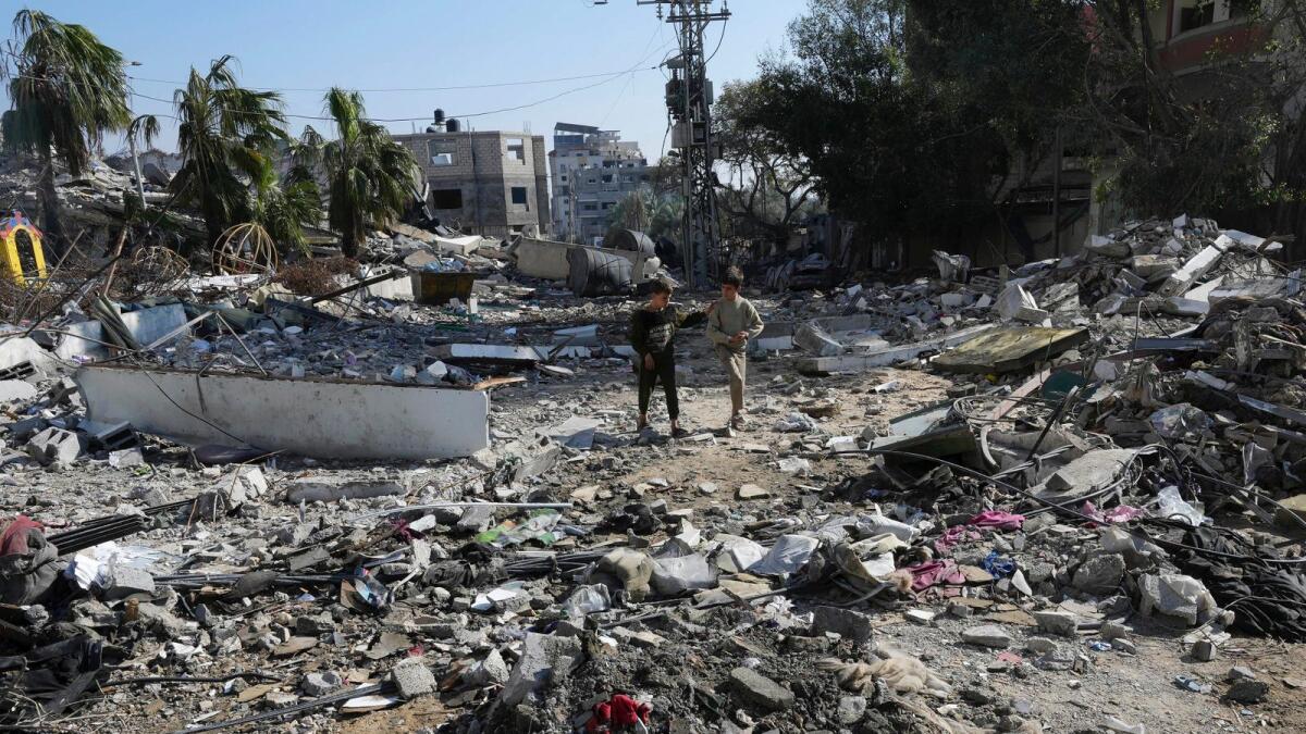 Palestinians walk through destruction from the Israeli bombardment in the Nusseirat refugee camp in Gaza Strip. — AP