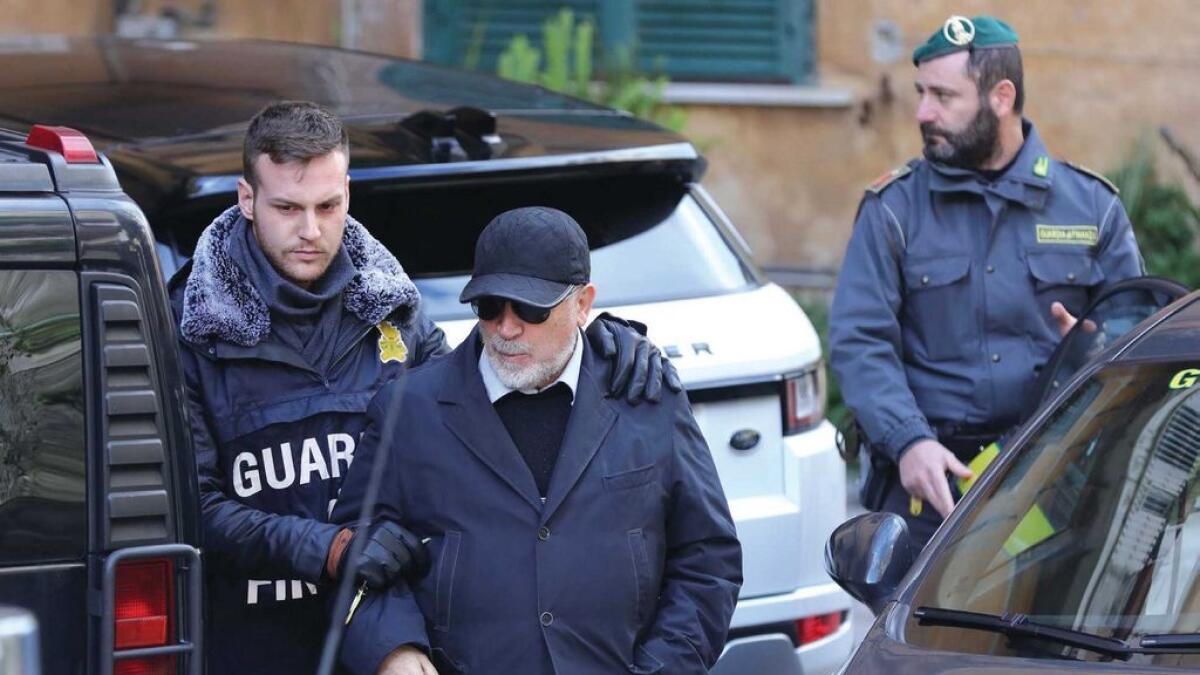 An Italian policeman escorts Italian Mario Di Leva, suspected of smuggling weapons to Libya and to Iran despite an embargo in San Giorgio a Cremano near Naples.  