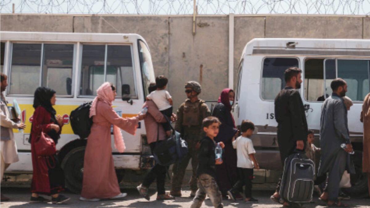 Evacuees line up to board buses during an evacuation at Kabul airport. — Reuters