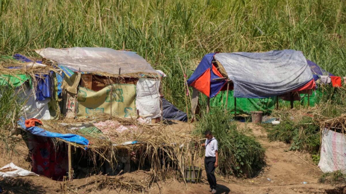 Ethnic Karen villagers, who fled recent attacks by the Myanmar military, carry on life in temporary shelters along the Moei River on the Thai-Myanmar border. — AP file