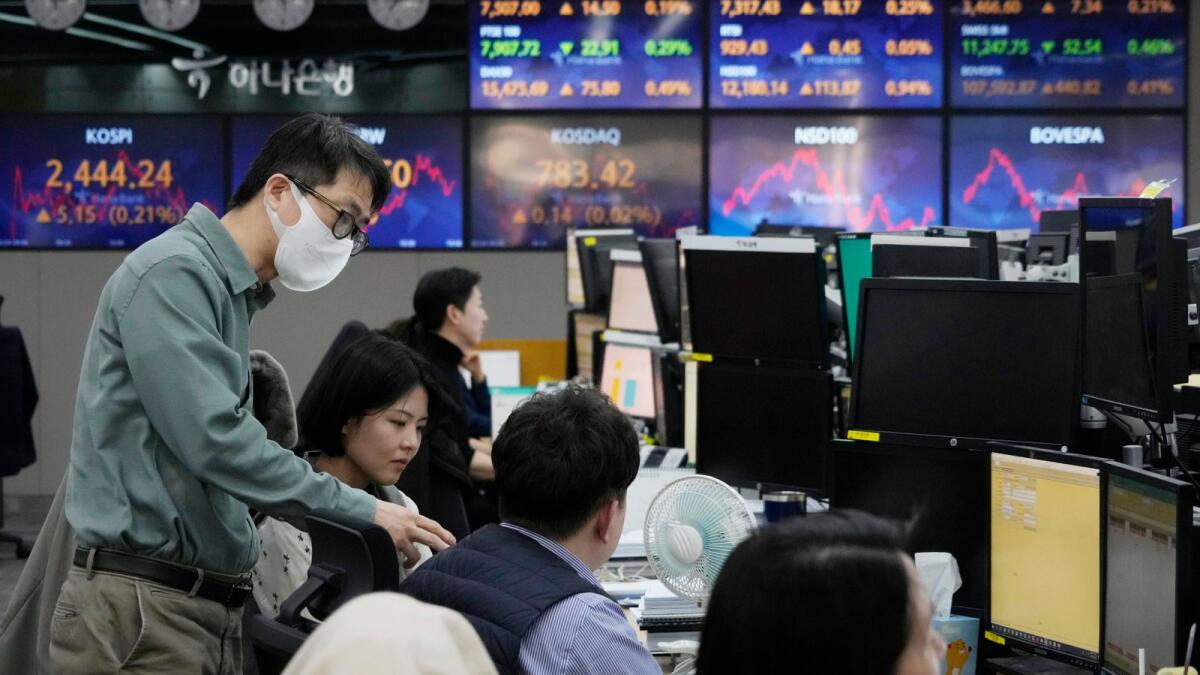 Currency traders work at the foreign exchange dealing room of the KEB Hana Bank headquarters in Seoul, South Korea on Friday. Shares in Asia were mixed on Friday after Wall Street broke its longest losing streak since December with a modest rally led by tech stocks. - AP