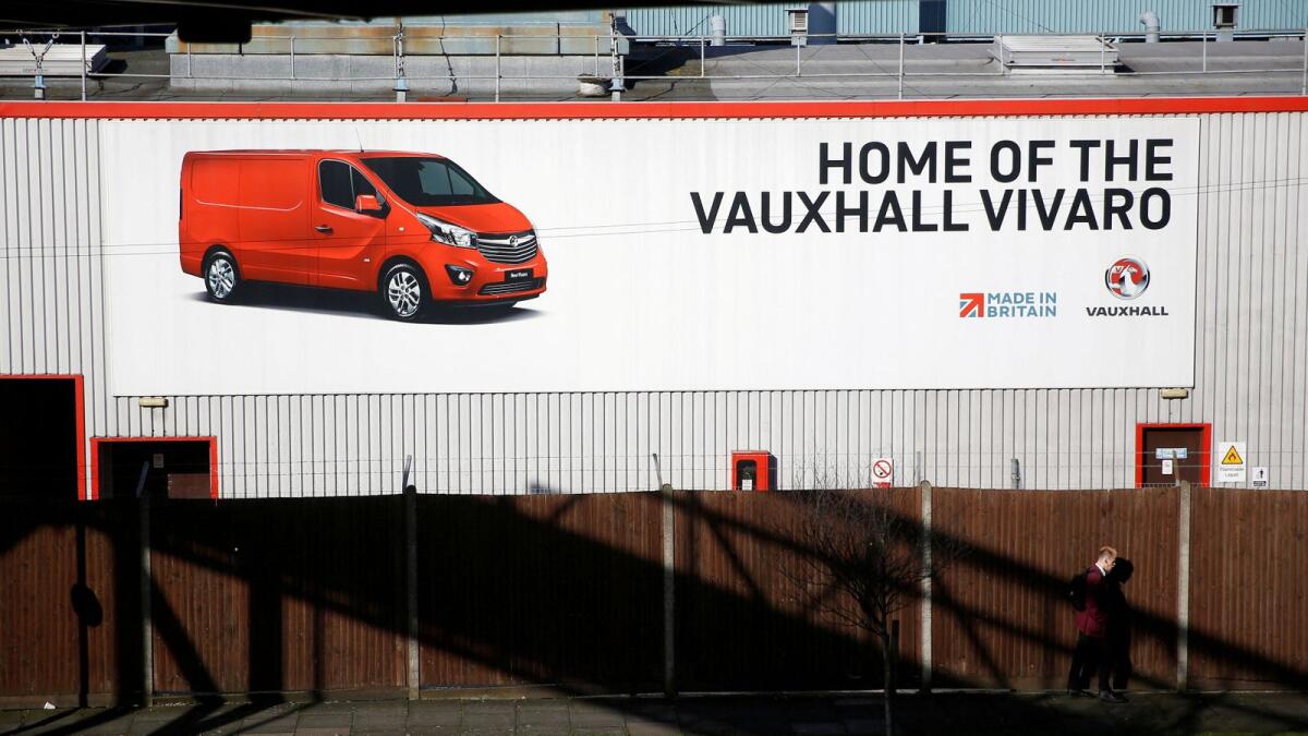 A person walks past a sign on Vauxhall's plant in Luton, Britain. — Reuters