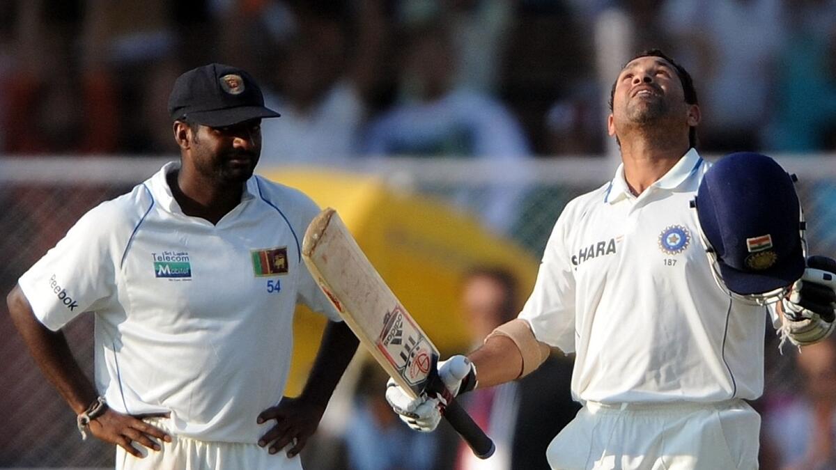 Sri Lanka's Muttiah Muralitharan (left) looks on as India's Sachin Tendulkar celebrates after reaching his century on the fifth day of the first Test in Ahmedabad on November 20, 2009. (AFP)