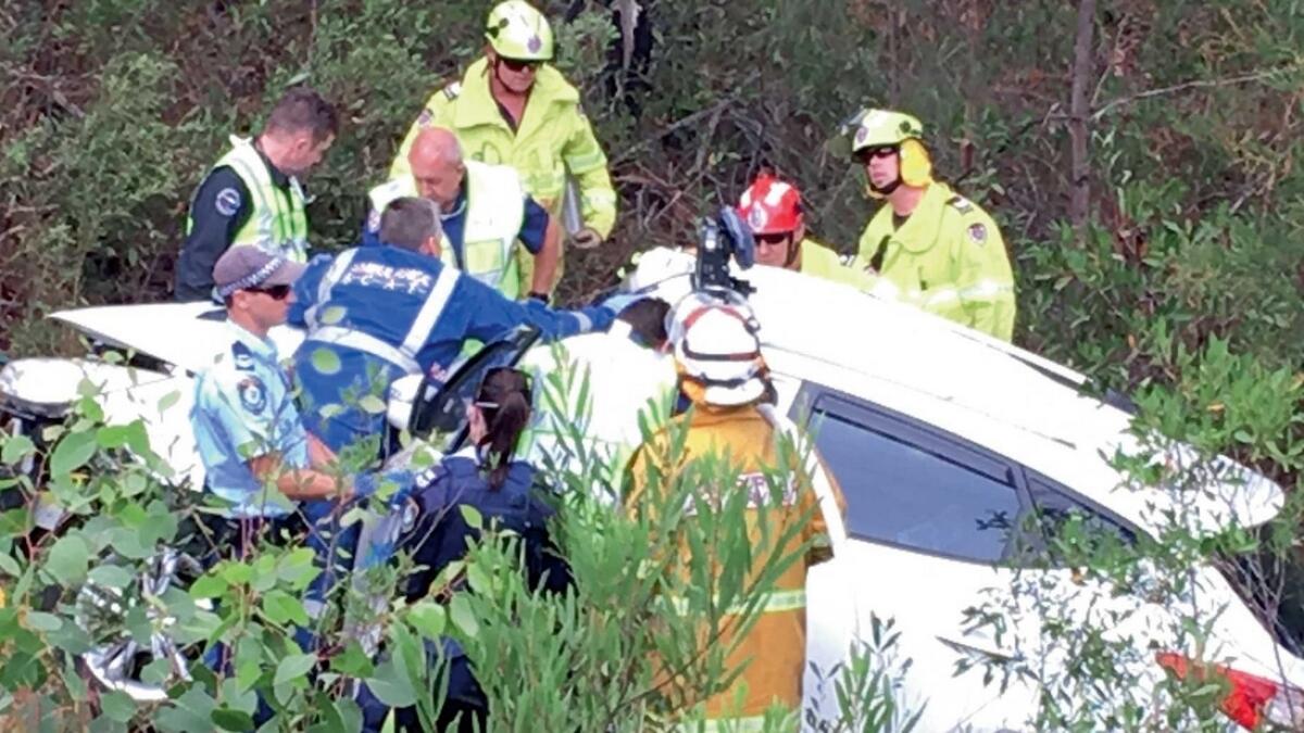 Emergency officers work to cut Samuel Lethbridge  from the wreck of his car off a highway in New South Wales. — AP