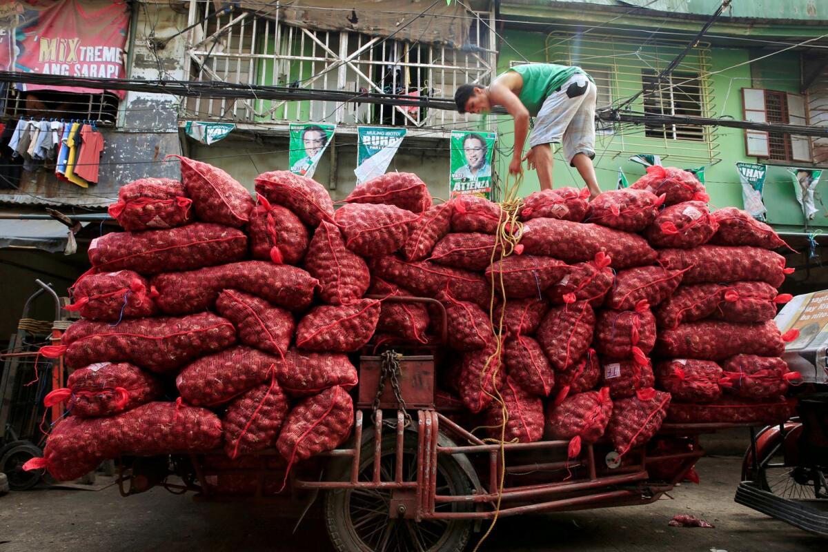 FILE. A worker stands on top of piles of red onion sacks. Photo: Reuters