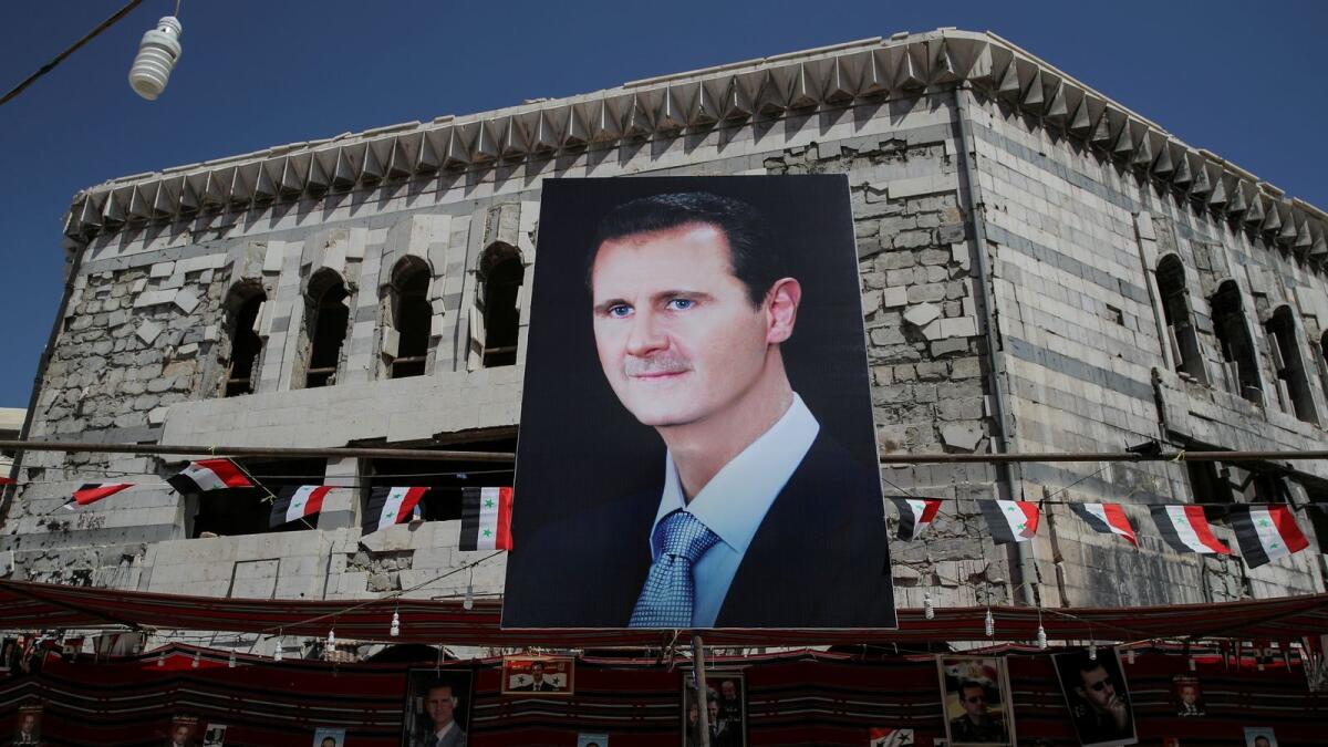 FILE PHOTO: A man walks past a banner depicting Syrian president Bashar al-Assad in Douma, outside Damascus, Syria, September 17, 2018. REUTERS/Marko Djurica/File Photo