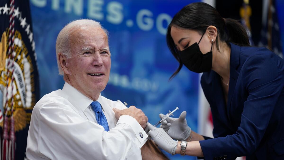 President Joe Biden receives his Covid-19 booster from a member of the White House medical unit during an event in the South Court Auditorium on the White House campus, on Tuesday. — AP photos