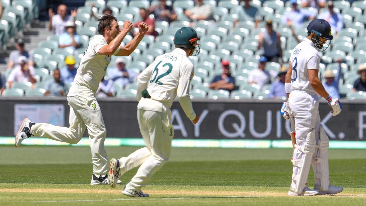 Australia's Pat Cummins (left) celebrtaes the dismissal of India's Virat Kohli on the third day of the first cricket Test. — AFP